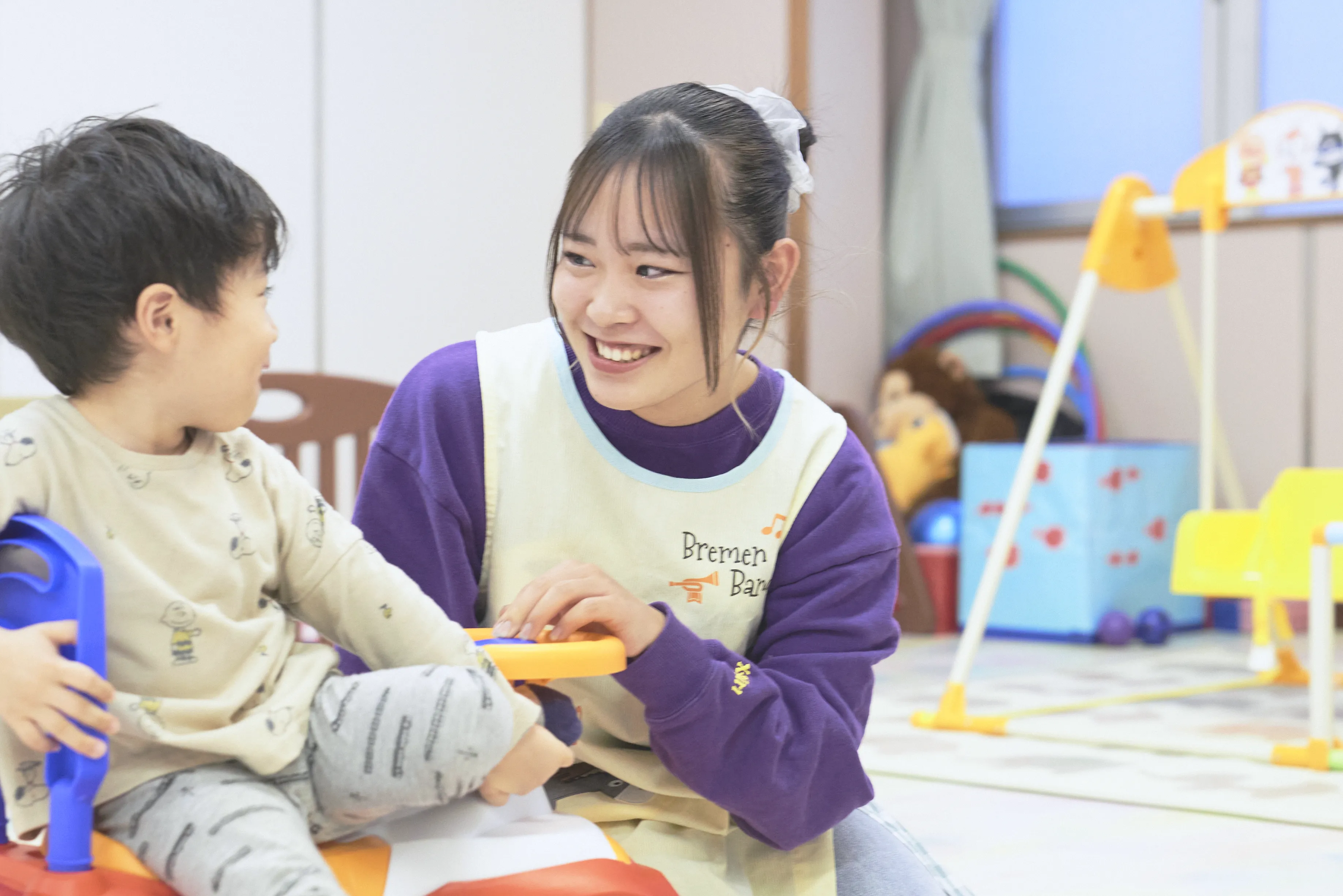 保育士がこどもを抱えている笑顔の写真